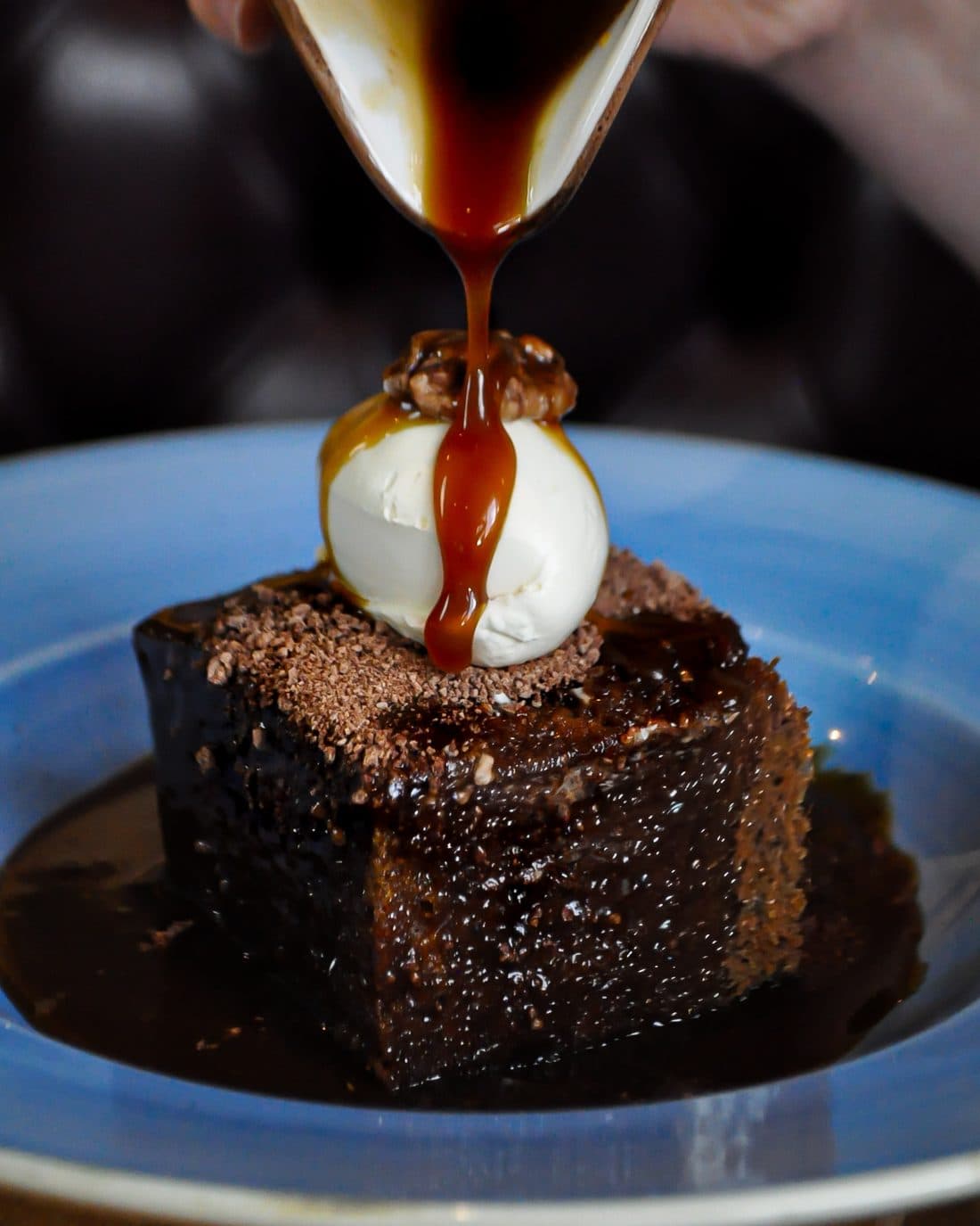 Sticky toffee pudding with caramel poured over clotted cream ice cream