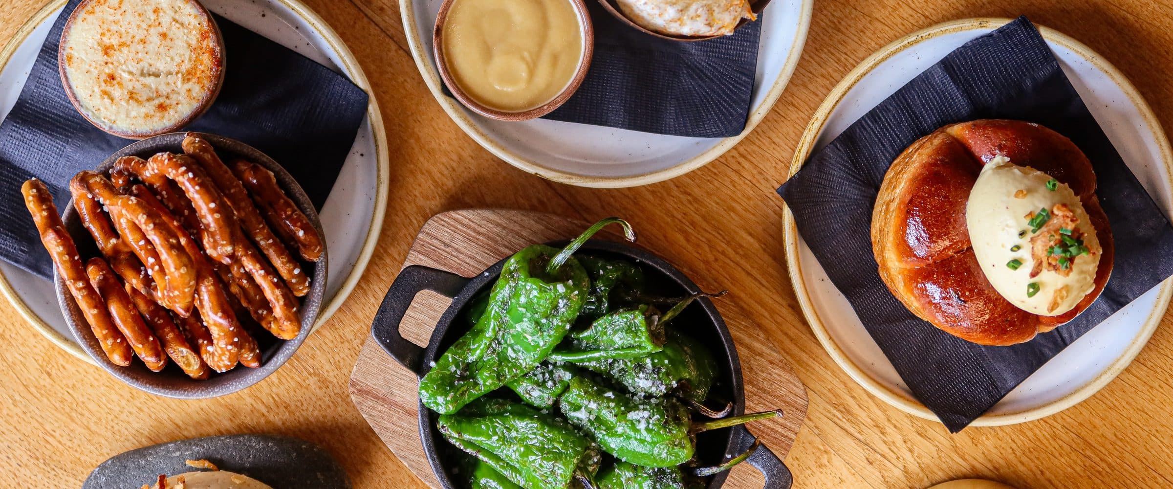 Pretzels, padrón peppers and brioche laid out to share